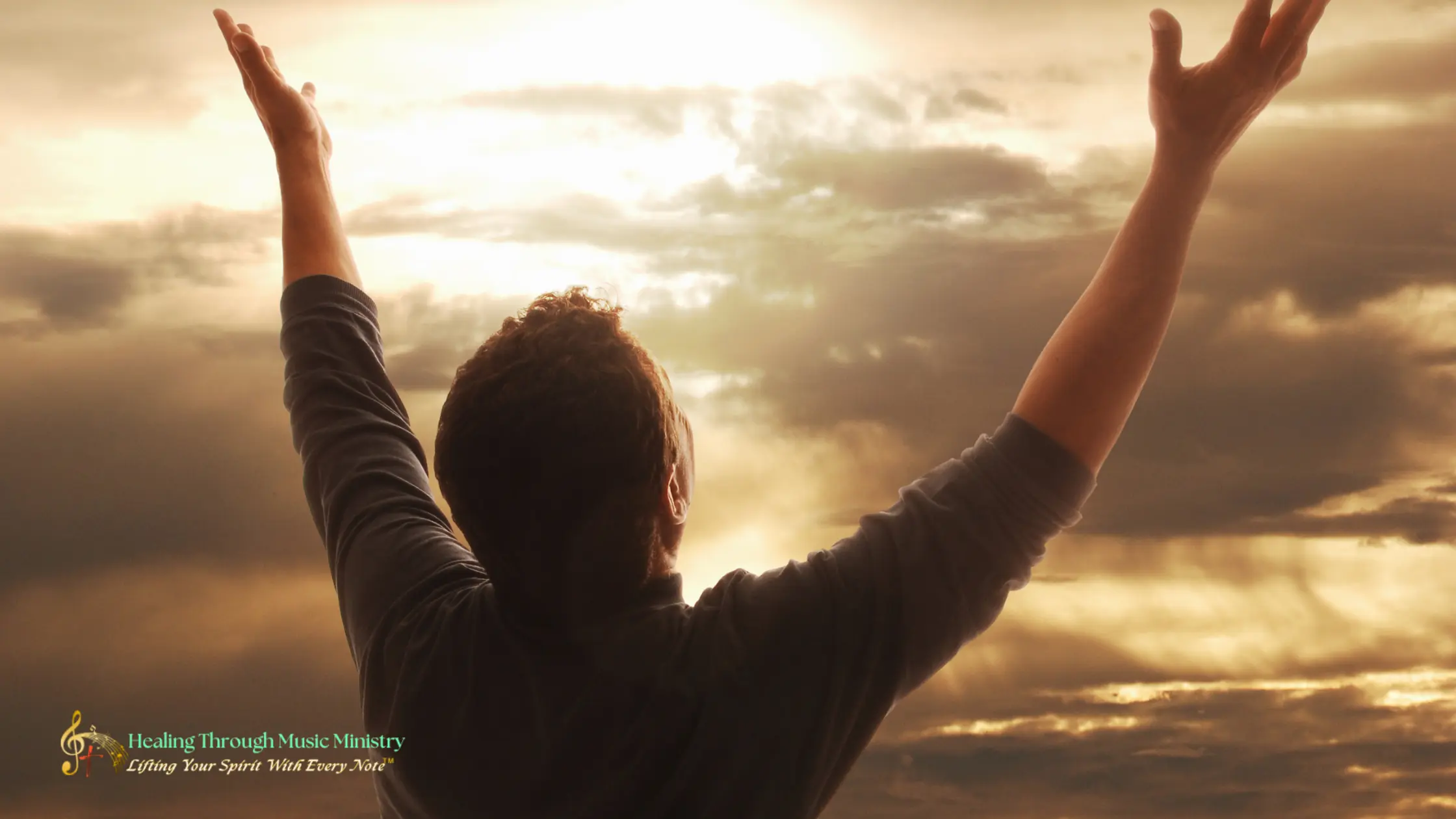 A person raising their hands toward the sky in worship as warm light breaks through the clouds.